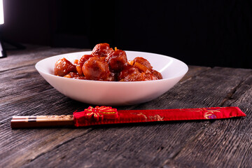 Meatballs with pineapple in sweet and sour sauce on wooden background. Chinese food. Asian cuisine