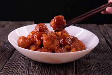 Meatballs with pineapple in sweet and sour sauce on wooden background. Chinese food. Asian cuisine