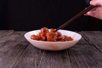 Meatballs with pineapple in sweet and sour sauce on wooden background. Chinese food. Asian cuisine