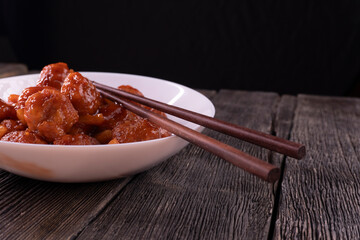 Meatballs with pineapple in sweet and sour sauce on wooden background. Chinese food. Asian cuisine