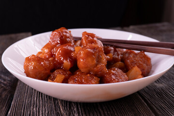 Meatballs with pineapple in sweet and sour sauce on wooden background. Chinese food. Asian cuisine