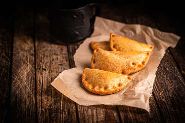 Traditional baked Spanish empanadas savory pastries with meat stuffing or vegetables against wooden background, fresh and homemade. Latin food.