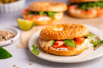 Healthy breakfast food. Bagel sandwich with salmon, cream cheese, cucumber and microgreens on white background. Burger with salmon.