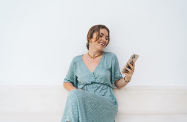 Joyful freelancer laughs holding phone, embracing lightness of mobile tech use and freedom of...
