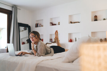 Confident freelancer gazes calmly while working on laptop, hand resting under chin, embodying...