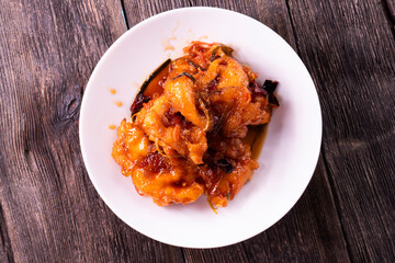 Fried chicken pieces in a sweet and spicy sauce on wooden background. Chinese food. Asian cuisine