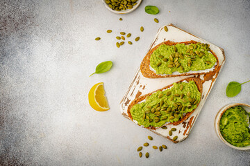 Healthy avocado toast for breakfast or lunch with whole grain bread and pumpkin seeds on a white table. Holistic nutrition concept. Health care, super food concept. top view