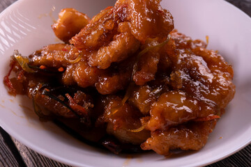 Fried chicken pieces in a sweet and spicy sauce on wooden background. Chinese food. Asian cuisine