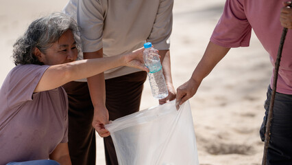 A group of older people are picking up trash on the beach to help keep nature clean and beautiful.