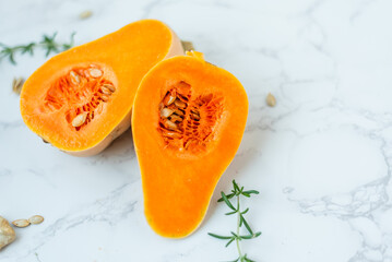 Halved butternut squash with seeds on marble surface.