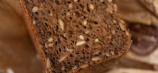 closeup of homemade sourdough rye bread with seeds on brown paper, artisan rustic wholegrain loaf, textured dark crust, healthy baking concept of organic bakery, nutrition, food blog