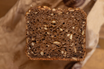 closeup of homemade sourdough rye bread with seeds on brown paper, artisan rustic wholegrain loaf, textured dark crust, healthy baking concept of organic bakery, nutrition, food blog