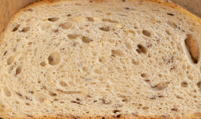 white sandwich bread slice with oat and flax seeds on wooden surface, closeup macro texture showing porous crumb and soft structure, perfect for toast or healthy breakfast, food packaging and bakery 