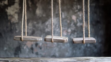 Rustic wooden swings hanging from ropes in aged concrete background for nostalgic childhood concept