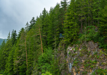 beautiful and dramatic landscape with mountains and forest against a cloudy sky, man on observation...