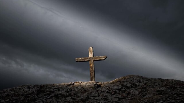 Wooden cross illuminated on rocky hill under dramatic sky during twilight