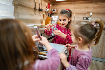 Sisters enjoy a playful cooking session together in a cozy modern kitchen filled with warmth and...