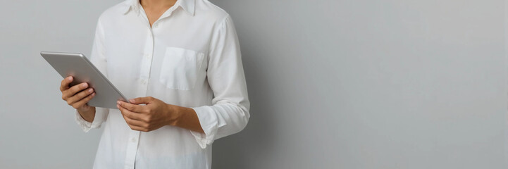 Woman in white shirt browsing on a tablet showcasing modern work and digital lifestyle with neutral