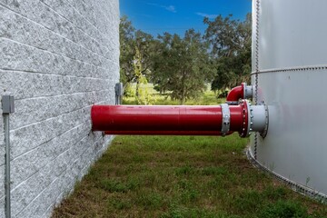 Red metal industrial pipe connecting tank for water or fuel to other structure