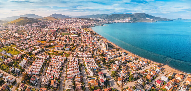 Drone capturing the cityscape of Dikili, its residential neighborhoods, the Aegean Sea, and the surrounding mountains in Turkiye
