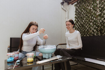 Two teenage sisters make cotton candy in their backyard.