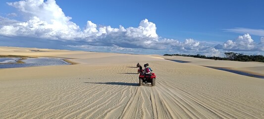 Lençóis Maranhenses. Group of tourists riding quad bikes on an adventurous tour through sand...