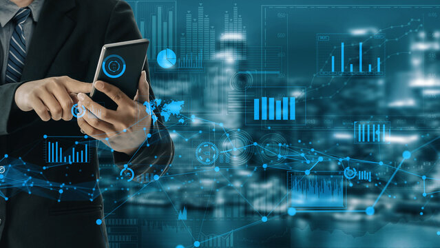 A businessman interacts with a smartphone displaying digital analytics against a modern city backdrop, illustrating technology impact on business and innovation. Xenic