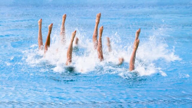Artistic swimmers team performing synchronized choreographed legs movement in the swimming pool