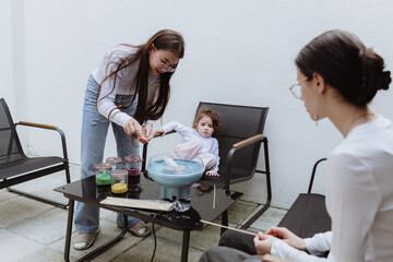 Three cheerful sisters make cotton candy in their backyard.