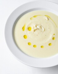 Creamy cauliflower soup with olive oil drizzle in a white bowl, a healthy gourmet lunch option