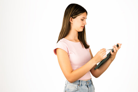 Teenage girl with straight brown hair in a pink shirt uses a digital tablet with a stylus, isolated on white. Suitable for technology, education, remote work, and digital lifestyle concepts.
