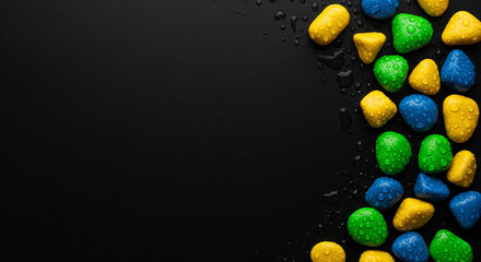 Colorful wet pebbles scattered naturally across a smooth dark surface