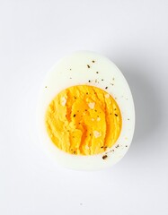 Perfectly seasoned hard boiled egg half showing vibrant yolk against a clean white background