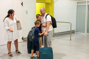 A happy wife with two sons meets her husband and father at the airport from a flight