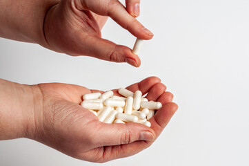 Close up of hands holding white capsules, representing health and medication.