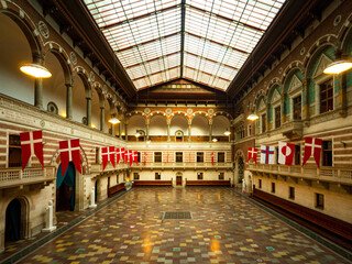 Elegant interior of Copenhagen City Hall, Denmark, featuring soaring arches, national flags, and a...