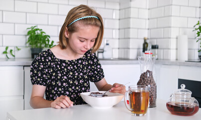 Little Girl Eating Dry Breakfast Cereal In The Kitchen For Breakfast