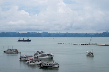 Construction site near the sea in Ha Long, Vietnam with cranes, buildings, and distant boats.