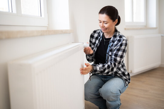 Woman Checks The Temperature And Adjusts The Heater At Home