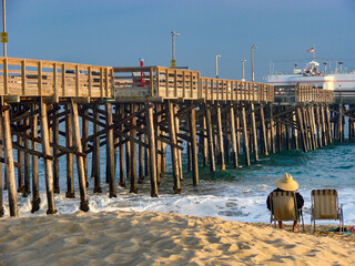 Man relaxing in beach chair at sunset, Balboa Pier, Newport Beach, California