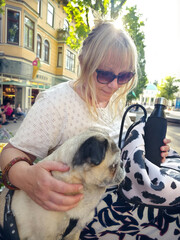 50-year-old woman sitting on a bench with a pug in Bad Pyrmont, Germany. Really smartphone photo.