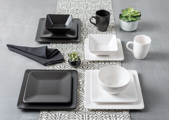 Top view of modern monochrome dining setup with matte black and white square dishware, geometric...