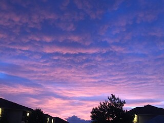 colorful sunrise with views of multiple rooftops and trees