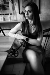 Portrait of a young beautiful dark-haired girl in a home studio. Black and white photo.