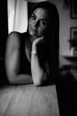 Portrait of a young beautiful dark-haired girl in a home studio. Black and white photo.