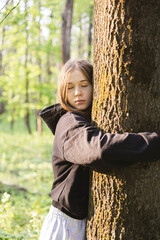 Teenage girl hugging tree, breathing fresh air and relieving stress in forest.