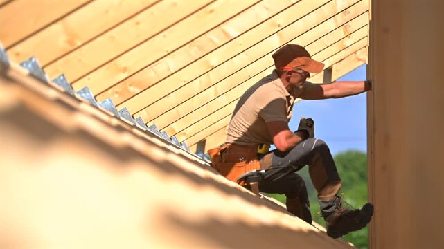 Skilled Worker Repairs Roof Using Tools and Climbing Safety Gear in Bright Daylight