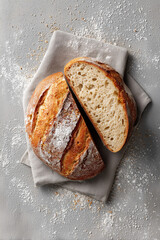 Photograph of a loaf of rustic bread, cut in half with the crumb visible, placed on a floured linen napkin.