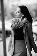 Young beautiful girl in an elegant suit with an umbrella outdoors. Black and white photo.