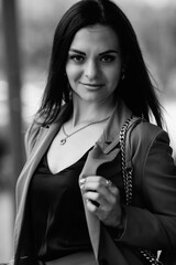 Young beautiful girl in an elegant suit with an umbrella outdoors. Black and white photo.